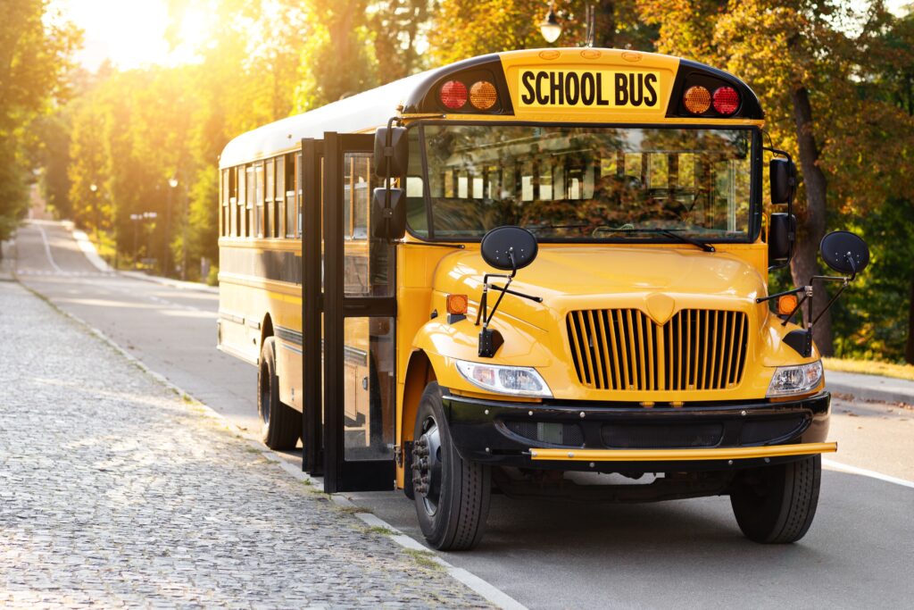 Yellow school bus parked on a sunny rural road with doors open, symbolizing safe and reliable student transportation - BusologyTech